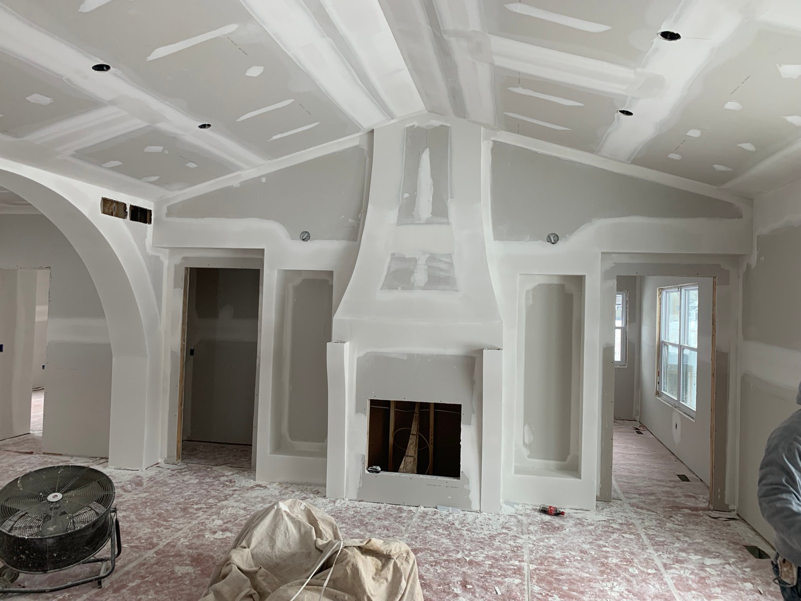 Interior of unfinished home with coffered ceiling, white walls, central fireplace